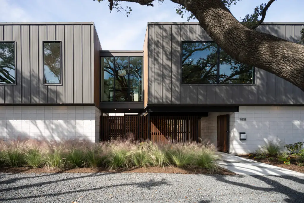 Modern two-story house with a gray exterior, large windows, and a contemporary wooden entry gate built after disaster recovery